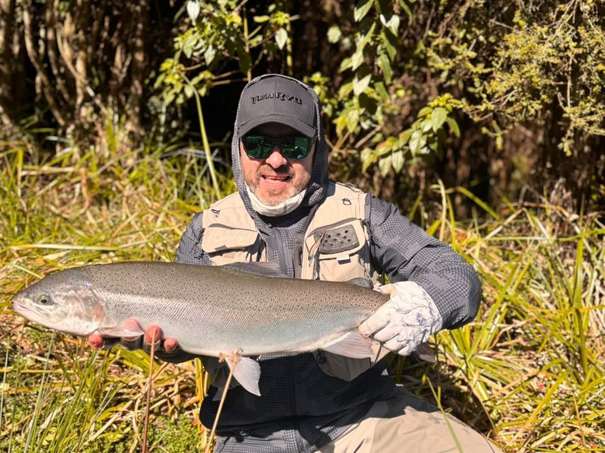 Carlos Yáñez con una trucha arcoíris en un río de la Araucanía