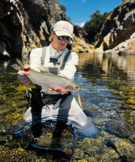 Nicolás Silva sosteniendo una trucha arcoíris en un río de montaña